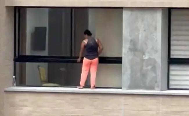 Una empleada limpia las ventas de un edificio sin ningún miedo